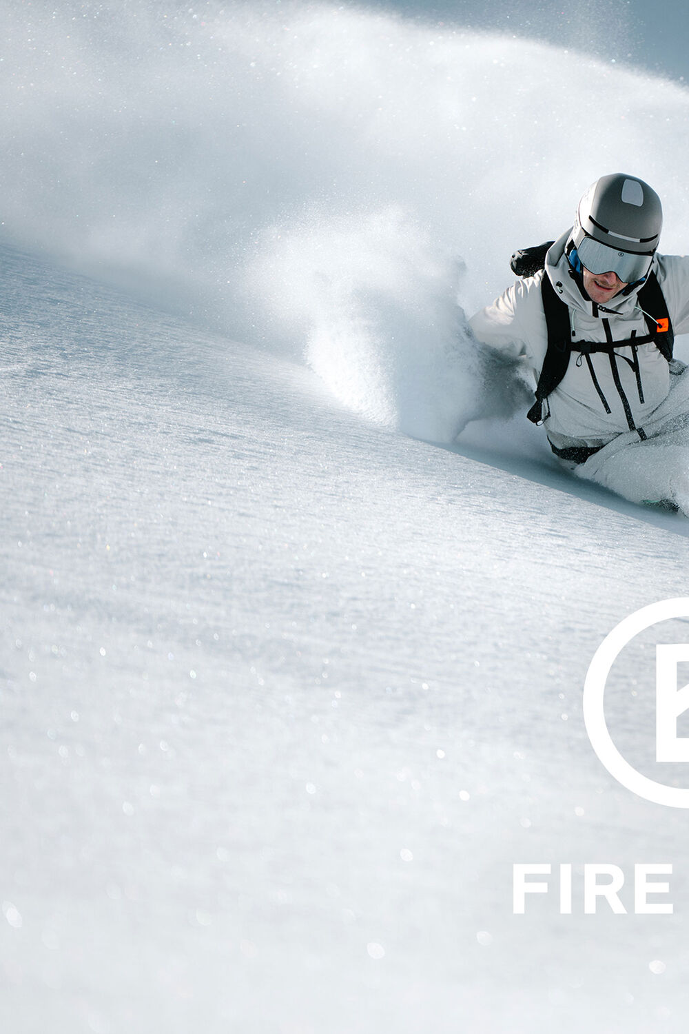 Das Herren Model in Action im frischen Schnee. Er tr&auml;gt einen hellen Skianzug mit Akzenten in Schwarz, dazu einen silberfarbenen Skihelm.