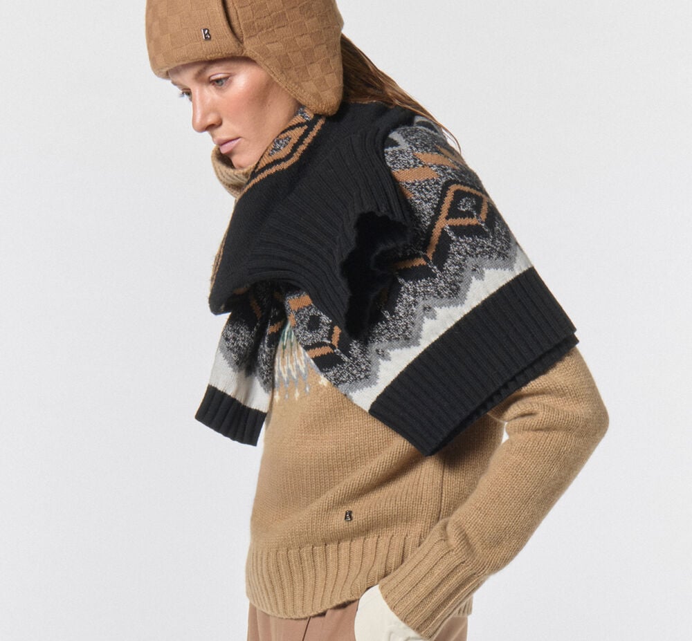 Creative styling of a Norwegian sweater wrapped around the model's neck. She is wearing a hat and a turtleneck sweater.