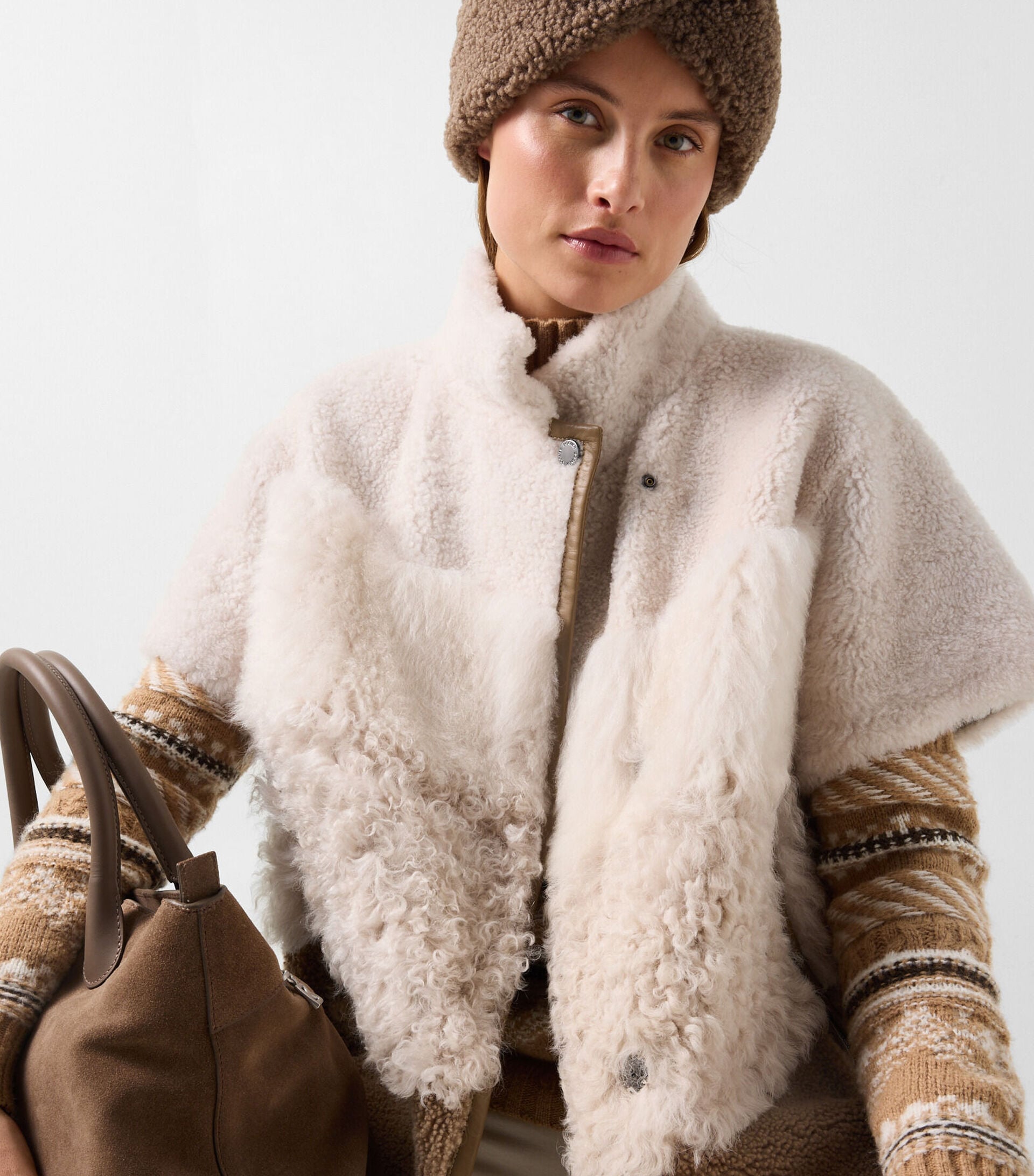 The female model wears the Lexy shearling jacket in cream and brown, paired with the Justy teddy headband in Hazel and the Rosa Nordic sweater in Camel.