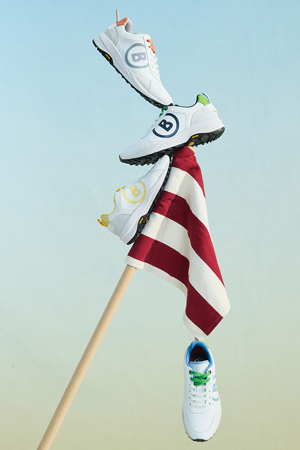 The new colourways of the BOGNER golf trainers, placed on a flag striped red and white.