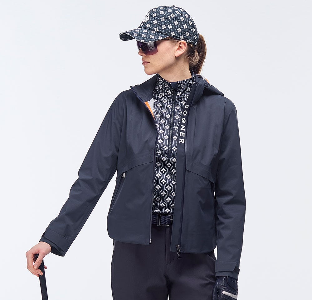 Die leichte dunkelblaue Jacke mit Logo-Details am Reißverschluss wird von einem Damenmodel getragen.