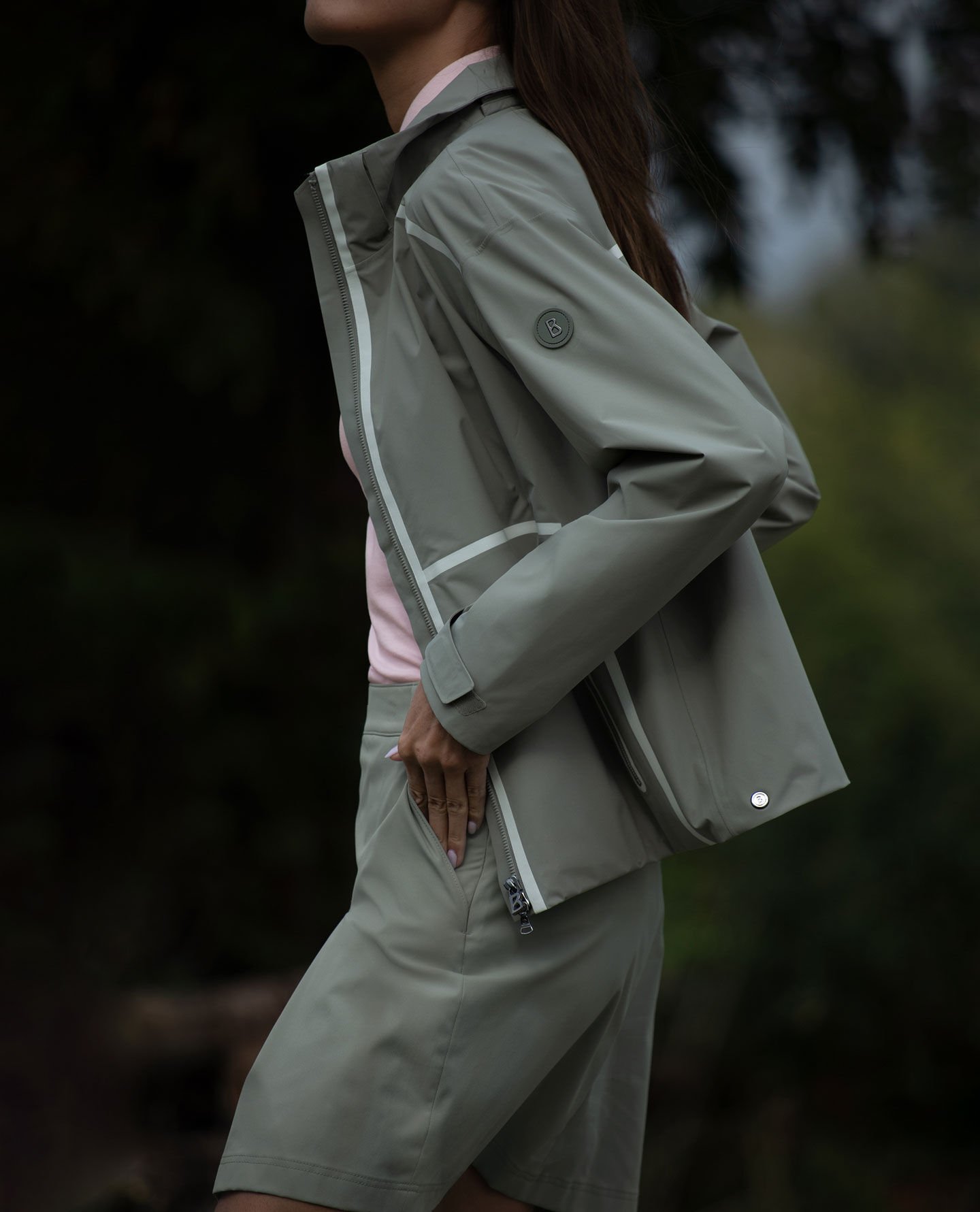 Side view of a lime green zip-up jacket. The female model is wearing short shorts with it.