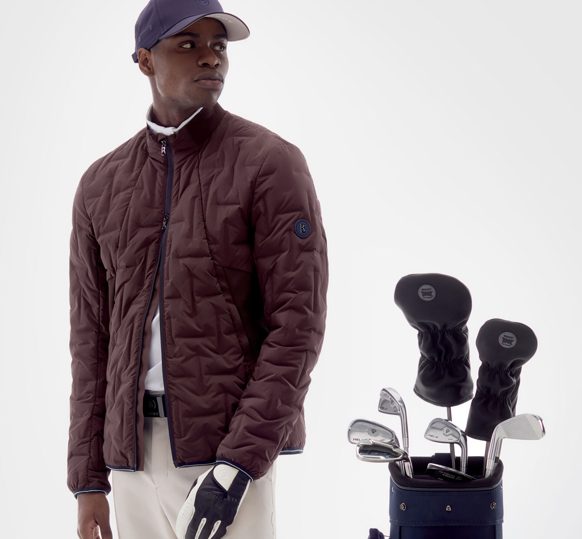 The model is wearing a wine-red lightweight down jacket from the Golf Collection, a cap and a pair of white golfing pants.