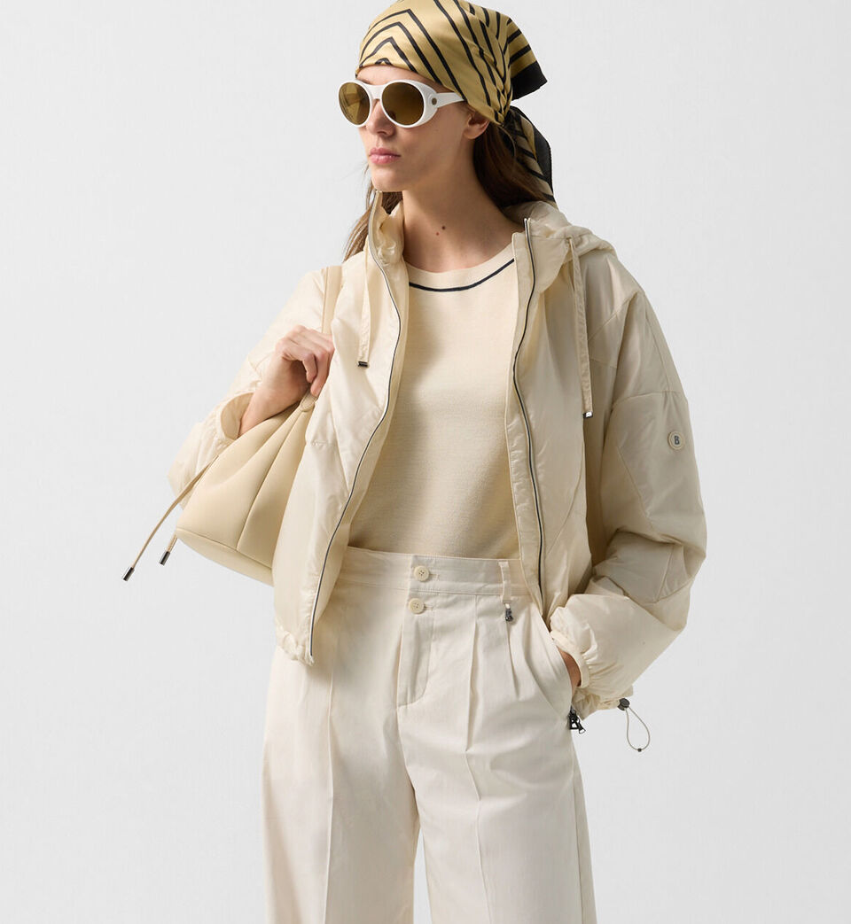 Halbk&ouml;rperaufnahme des Damen Models in Lightweight-Jacke Beryll in Creme. Sie tr&auml;gt dazu eine Sonnenbrille.