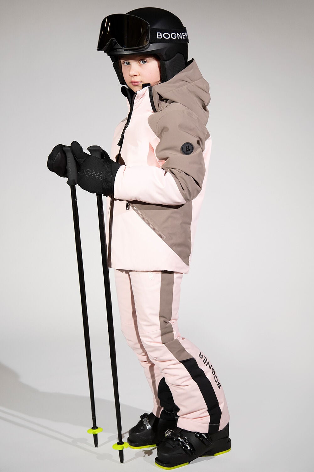 The girl is wearing a total ski look in pastel pink and brown finished off with a black ski helmet.