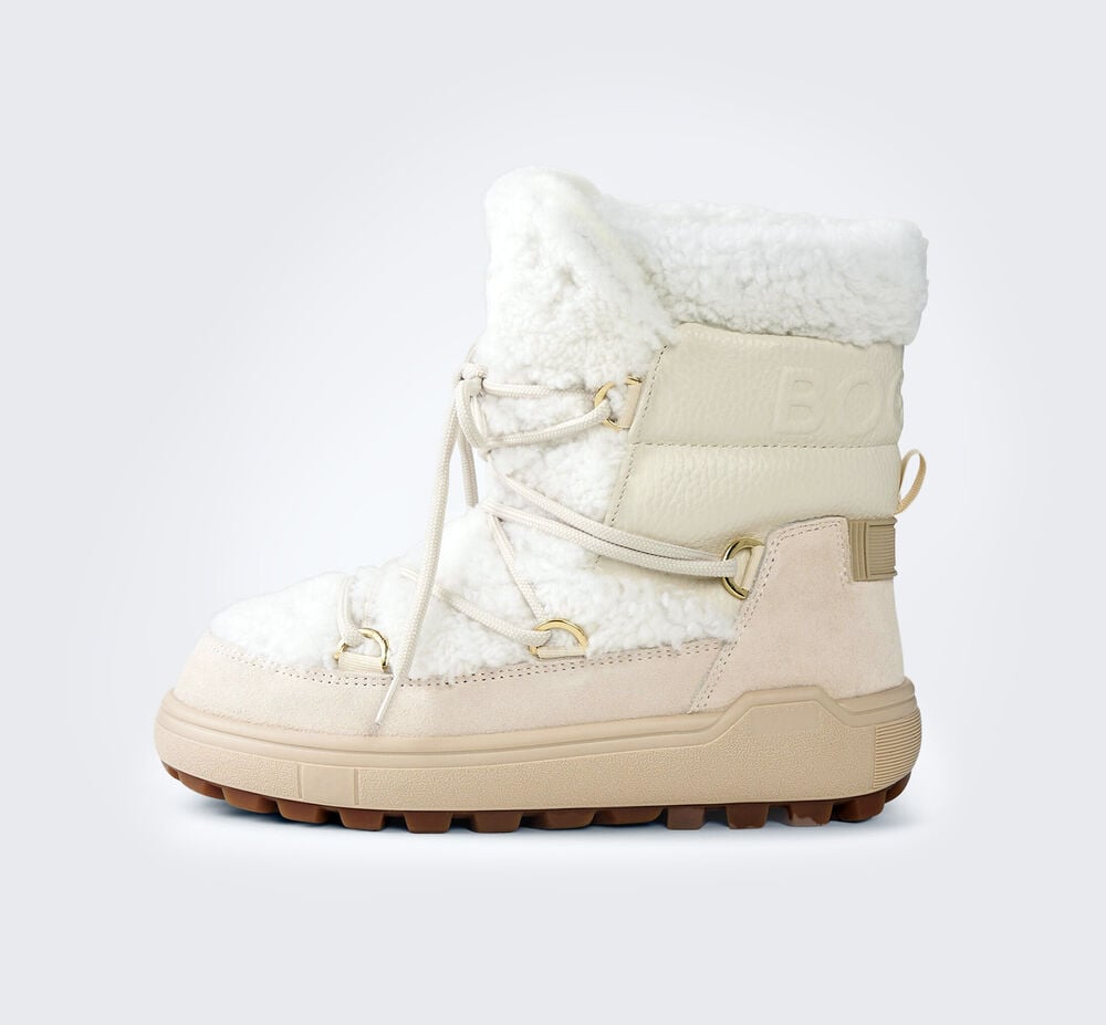 Seitliche Aufnahme cremefarbener Snow Boots, mit wei&szlig;em Fellbesatz, Eins&auml;tzen aus Veloursleder und Profilsohle.