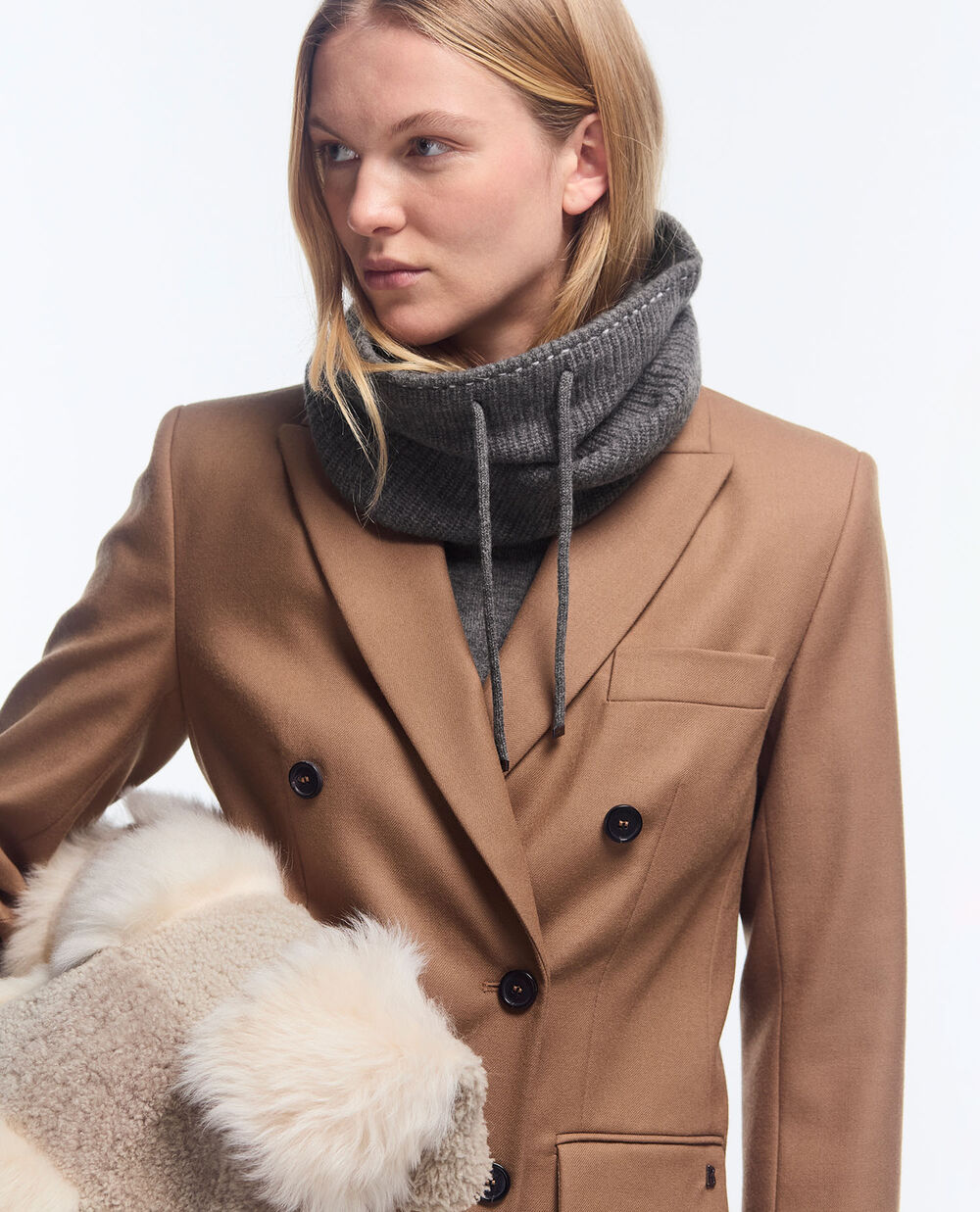 The camel-coloured blazer with peak lapels and distinctive shoulders is complemented by a turtleneck pullover in grey.