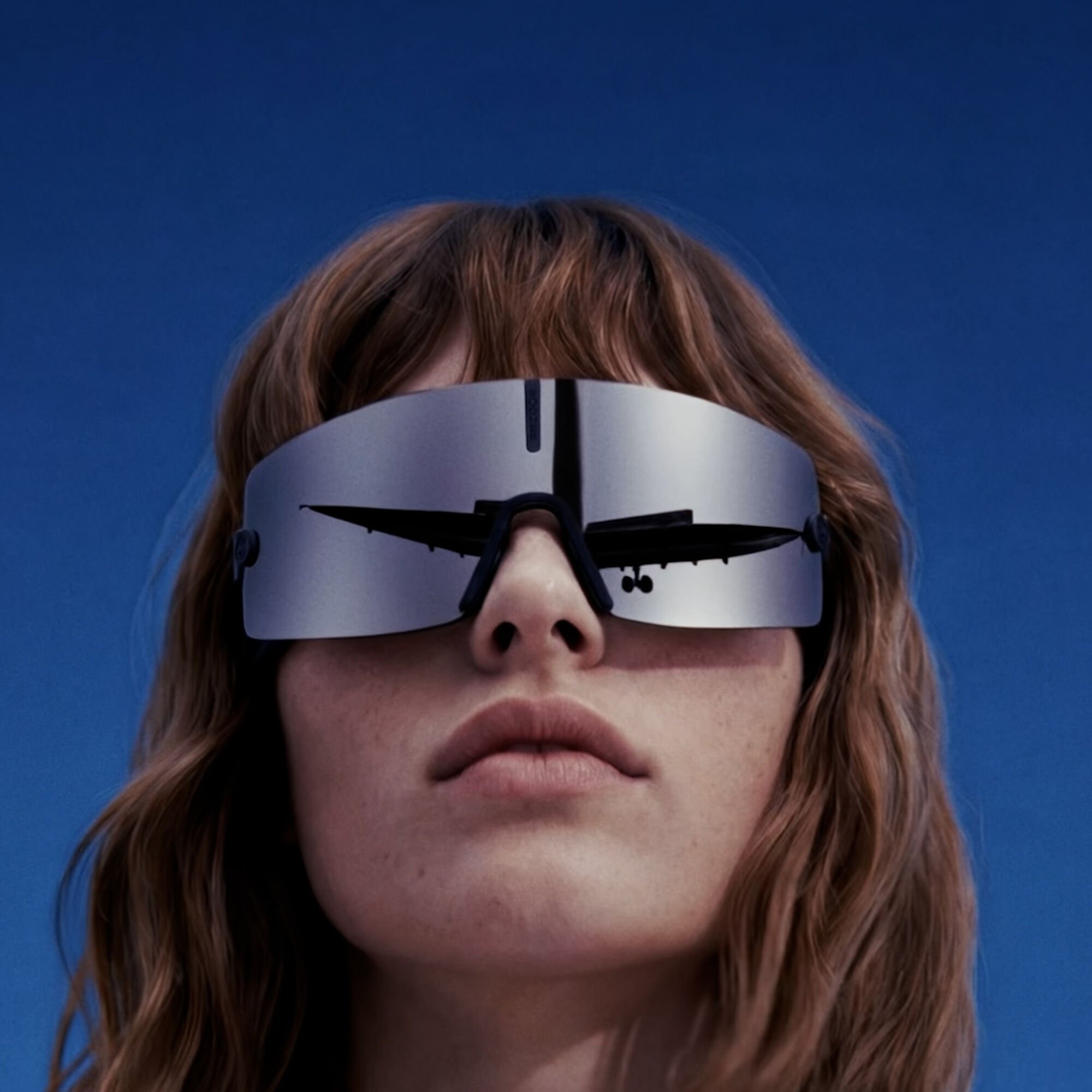 The female model is wearing polarised sunglasses in which the reflection of an aeroplane can be seen.