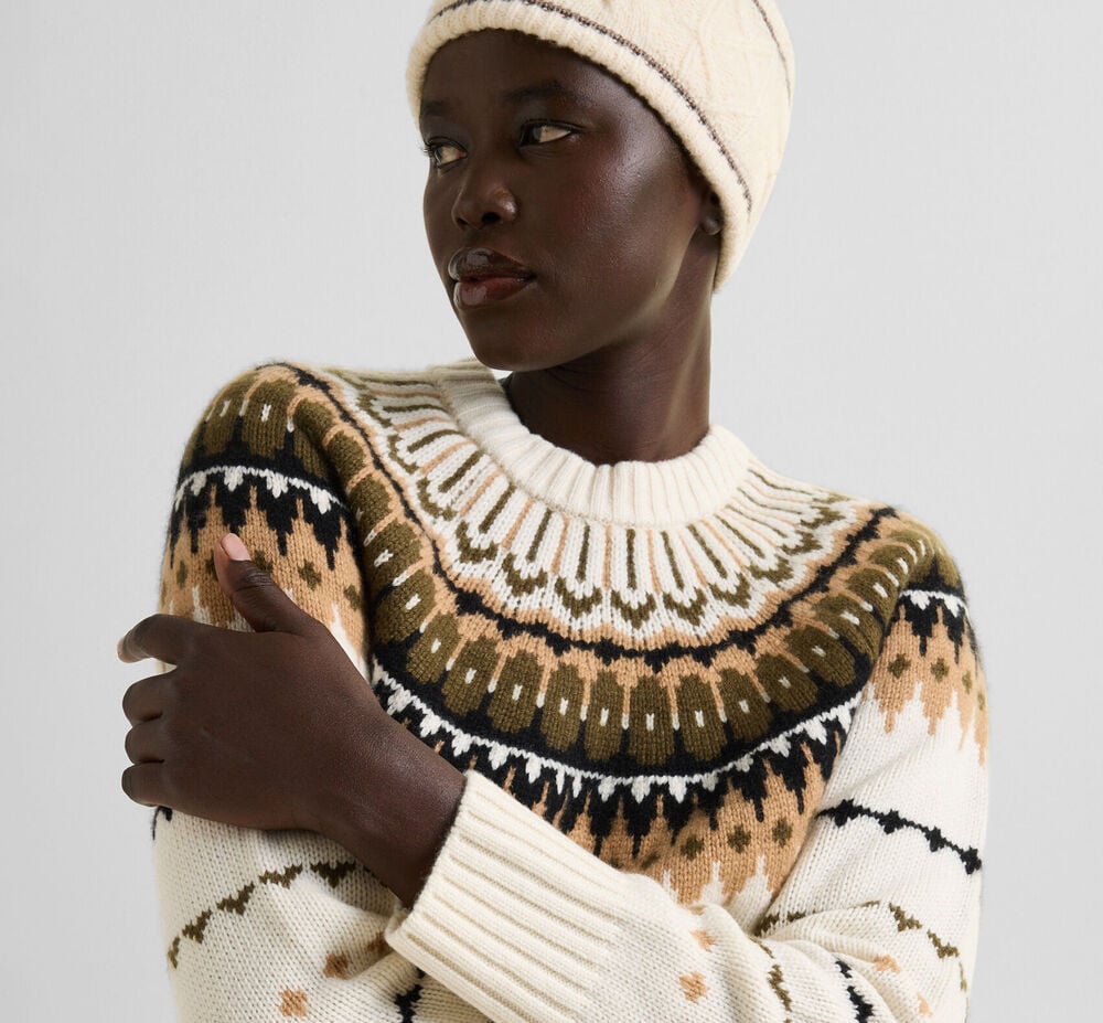 The female model is wearing an Ingrid pullover in white with the brand&rsquo;s signature Norwegian pattern in elegant earth tones, paired with a matching knitted hat.