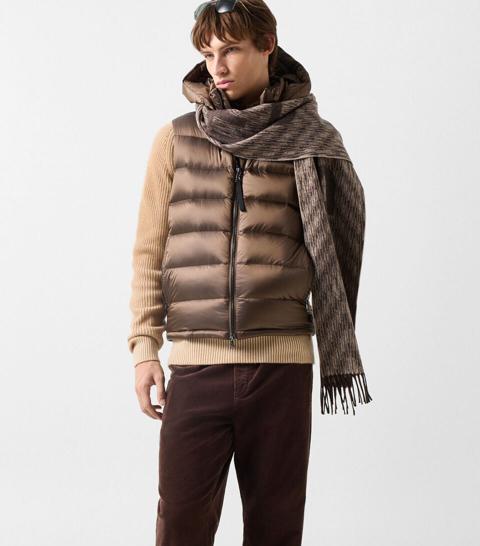 L&rsquo;autre mannequin homme porte le pull Dwayne &agrave; col montant zipp&eacute; en laine vierge et cachemire camel et cr&egrave;me, sous la doudoune sans manches Holger. Le pantalon Travis en velours c&ocirc;tel&eacute; coloris Coffee compl&egrave;te le look.