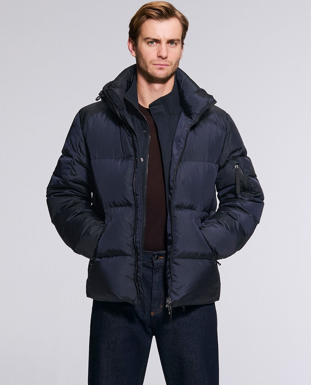 The model is wearing the classic Jamy down jacket with a detachable hood in navy blue.