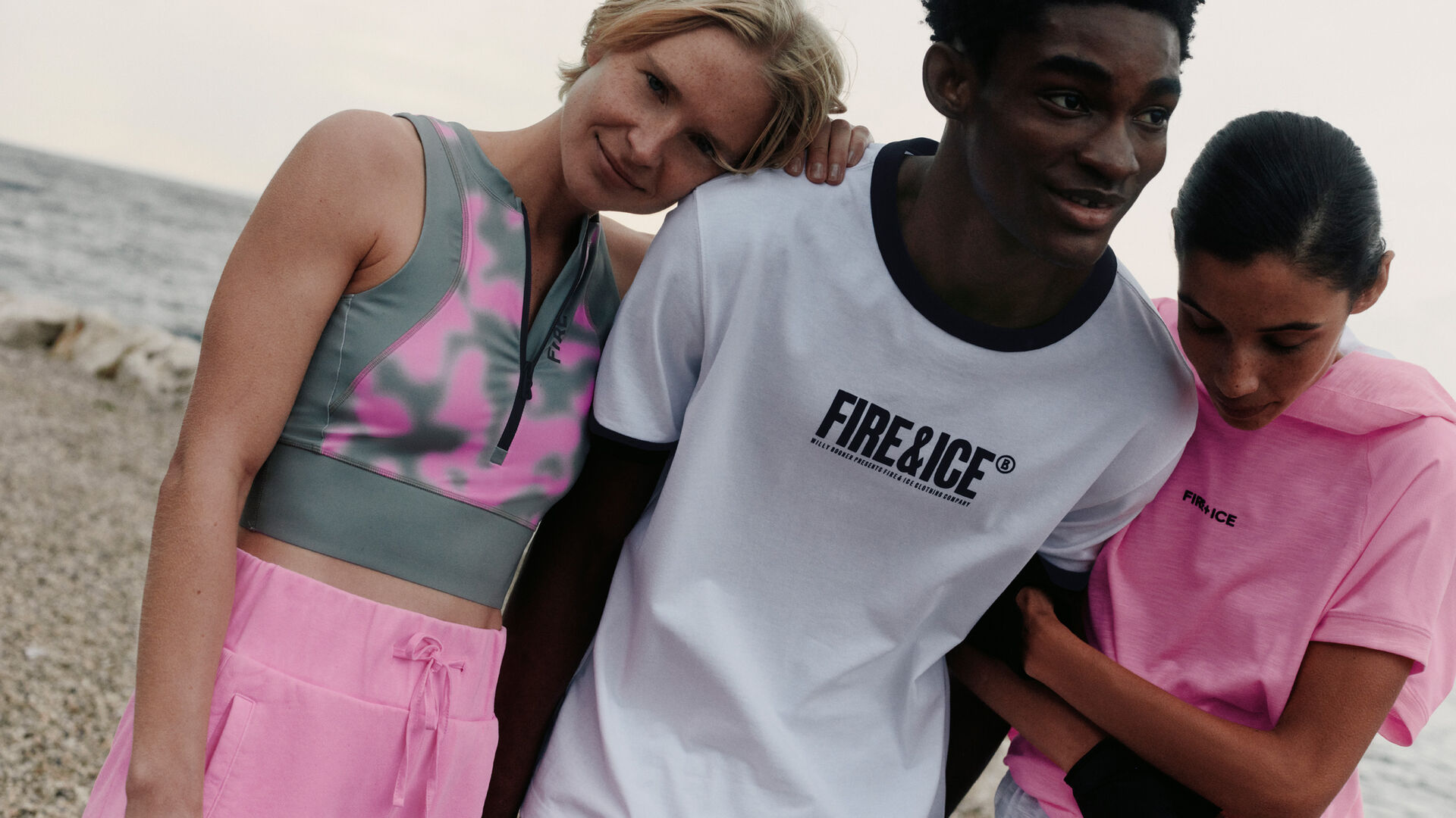 A group of three models, two female, one male, in FIRE+ICE looks. There is a lake in the background.