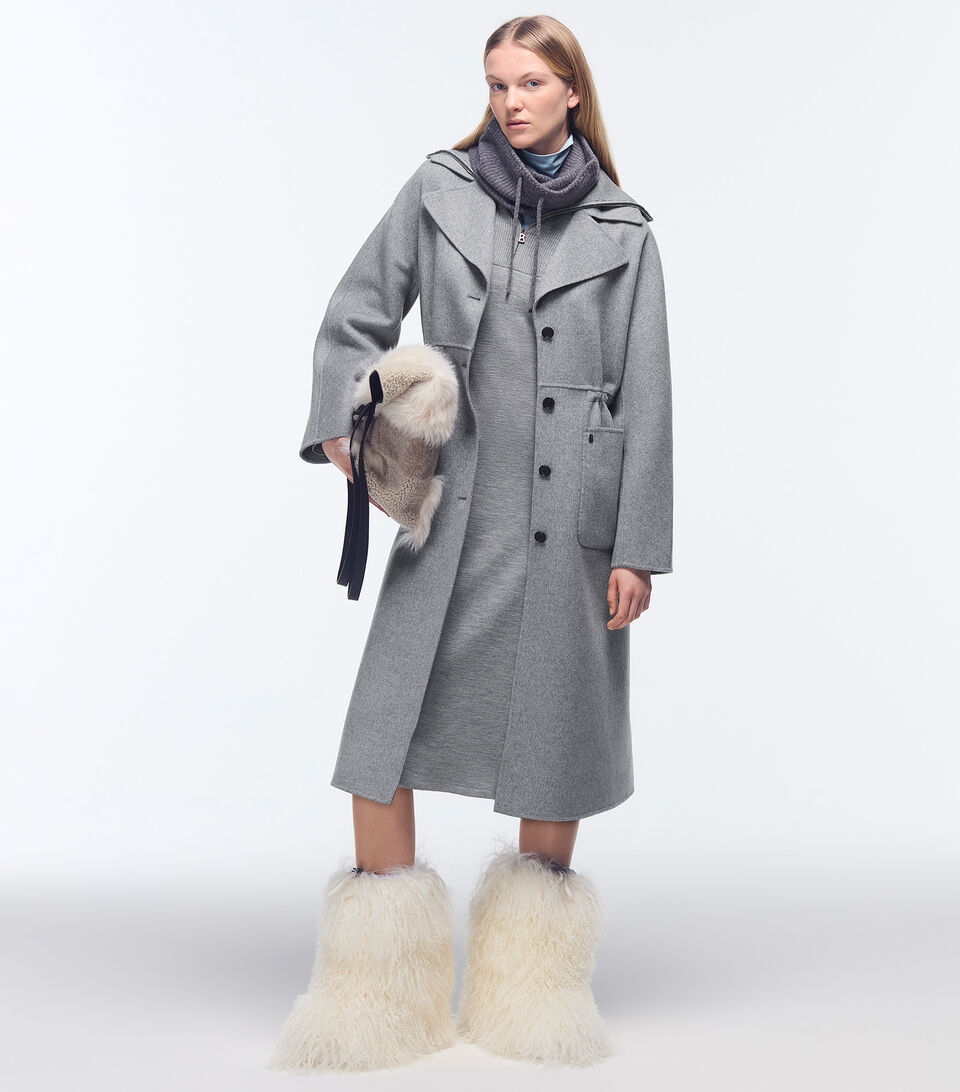 A shot of a total look in grey accented with a fur-trimmed bag and fur-trimmed white boots.