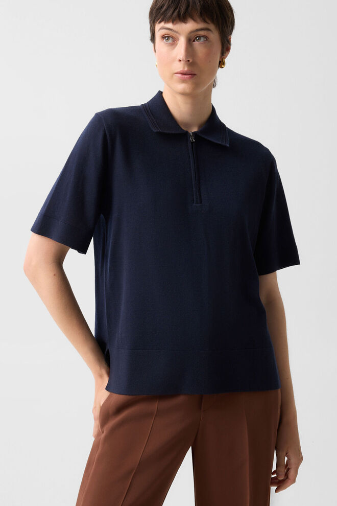 The female model is wearing the Enrica crepe shirt in navy blue, featuring a boat neckline and flared three-quarter sleeves.