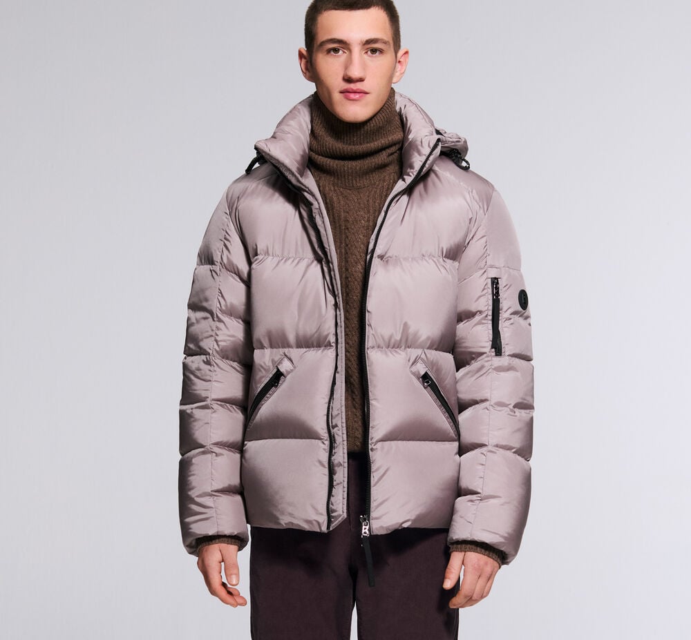The male model is wearing the Jamy down jacket in mauve, with a turtleneck pullover underneath. Dark trousers complete the look.