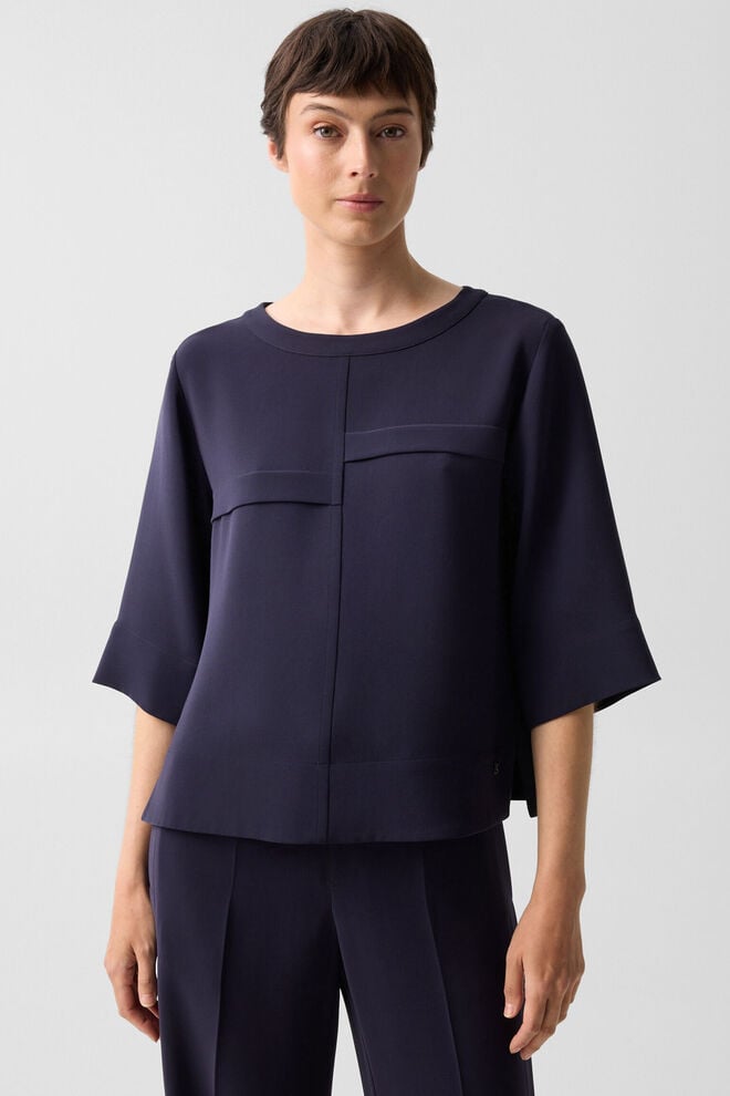 Das Damen Model tr&auml;gt Cr&ecirc;pe-Shirt Enrica in Navy-Blau mit U-Boot-Ausschnitt und ausgestellten Dreiviertel&auml;rmeln.