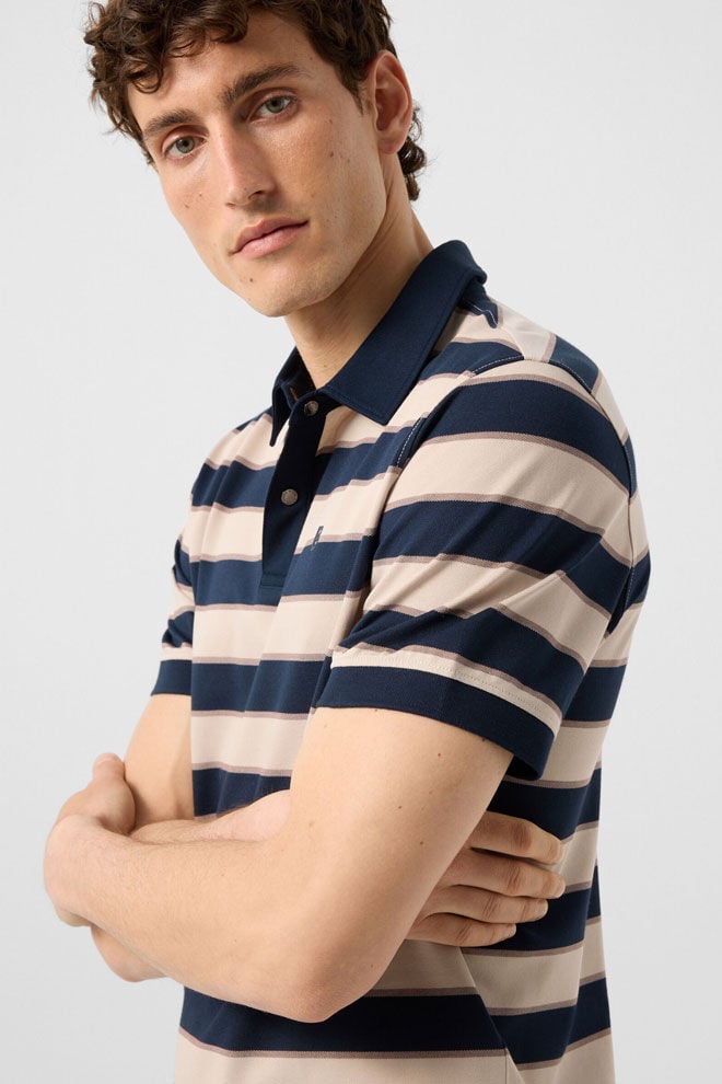 Das Herren Model tr&auml;gt das navyblau-sandfarben gestreifte Polo-Shirt Timo aus softem Baumwoll-Piqu&eacute;.