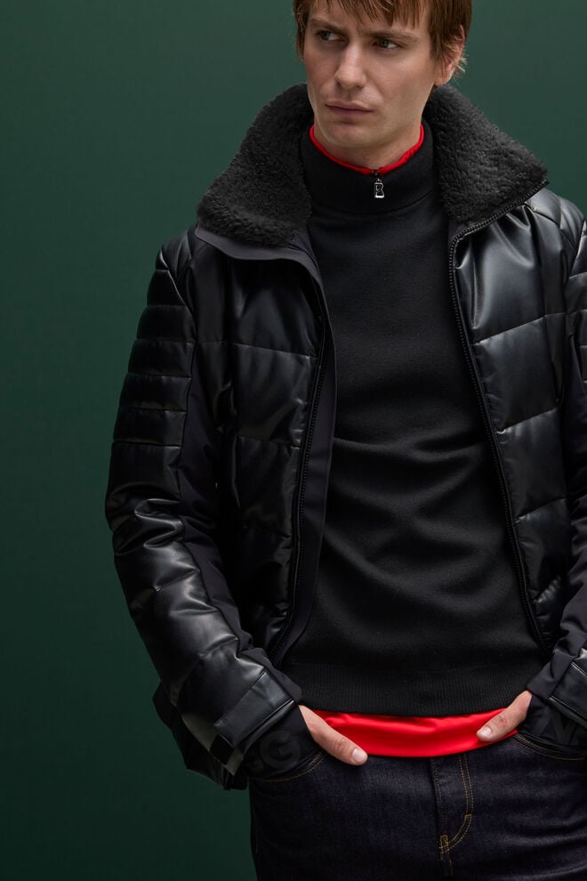 Le mannequin homme porte une veste matelassée noire effet cuir, agrémentée d’un col en teddy pour une touche de douceur et de style urbain. Avec un pull rouge.