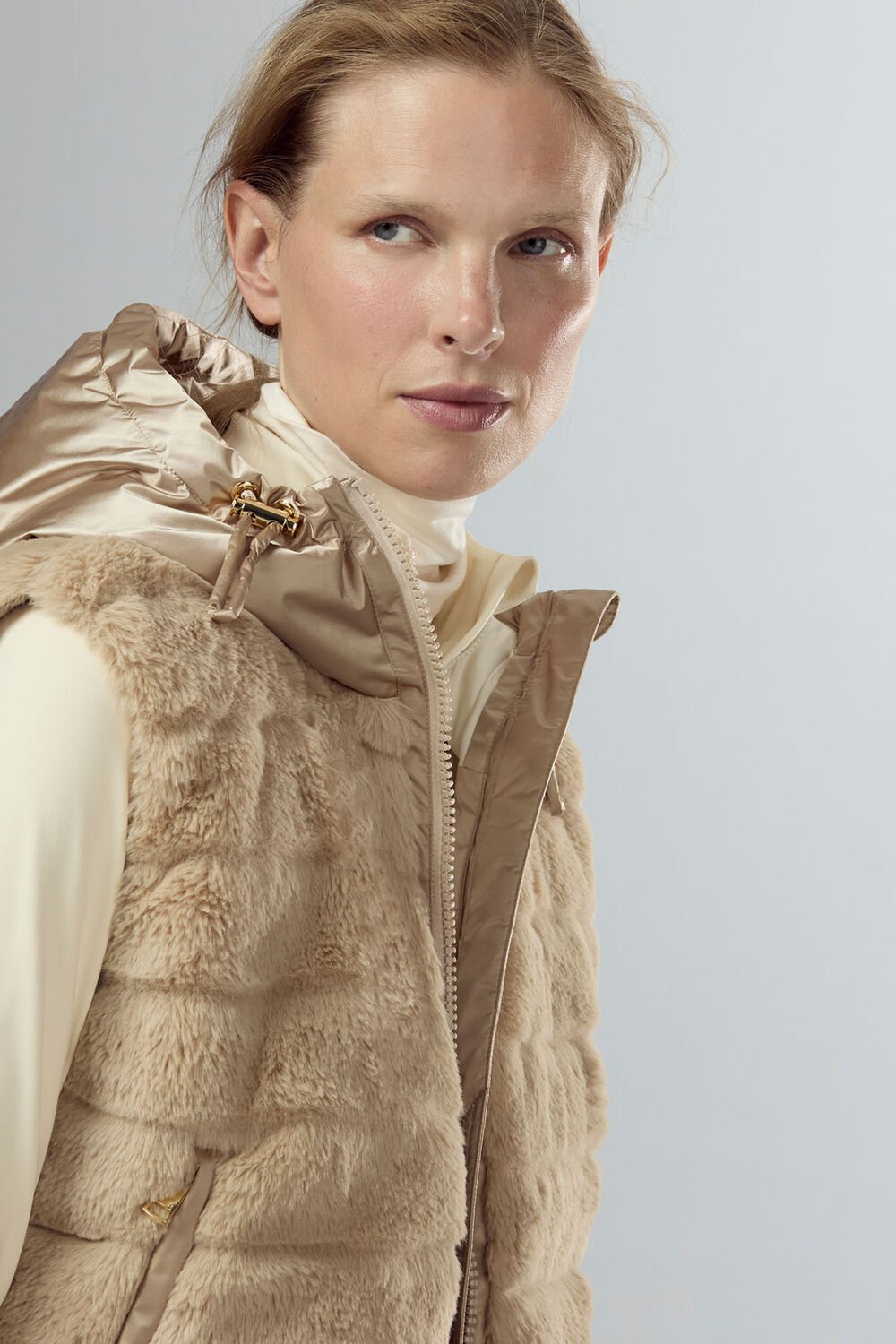 Nahaufnahme des Damen Models, das eine teddybesetzte Weste mit Kapuze und darunter einen Rollkragenpullover trägt. Nahaufnahme des Damen Models, das eine teddybesetzte Weste mit Kapuze und darunter einen Rollkragenpullover trägt.