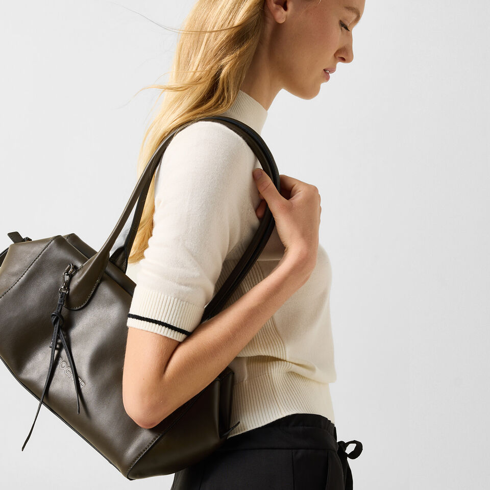 Das Model tr&auml;gt den Aletsch Binia Shopper &uuml;ber der Schulter, der aus olivgr&uuml;nem Leder gefertigt wurde.