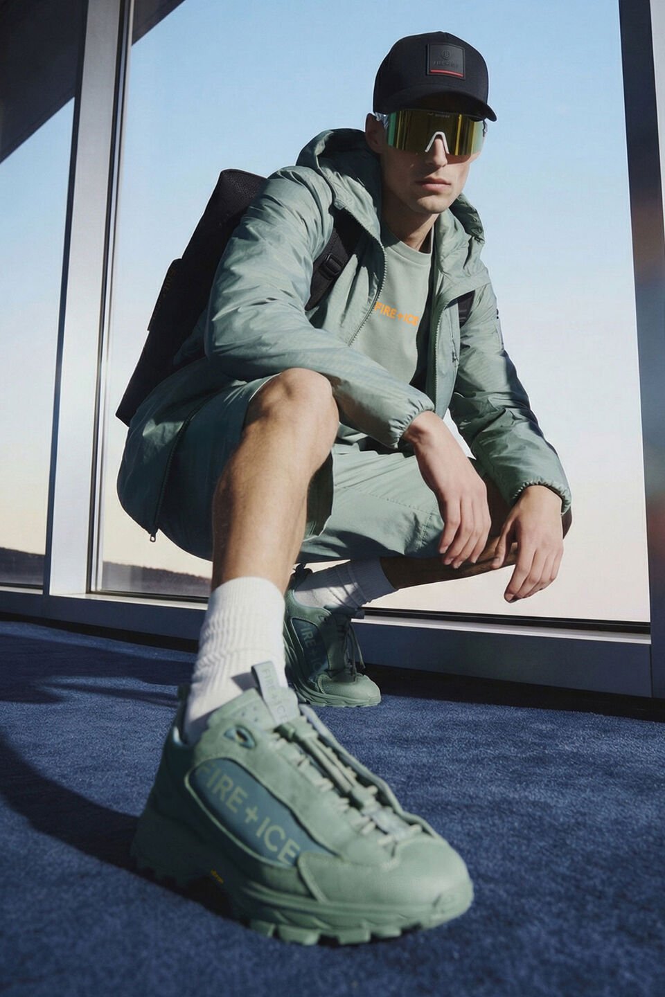 Two models sitting next to each other. The male model is wearing the Montana trainers in grey, the female model is wearing the Lake sandals in black. 