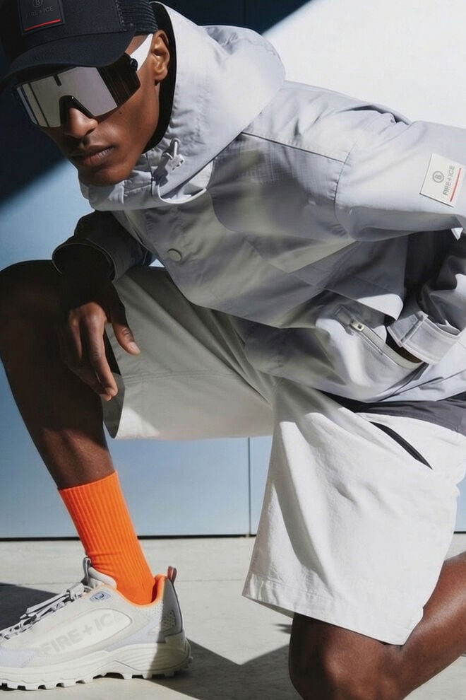 The male model, who is crouching down, is wearing a monochrome outfit in light grey with orange accents and the Montana trainers.