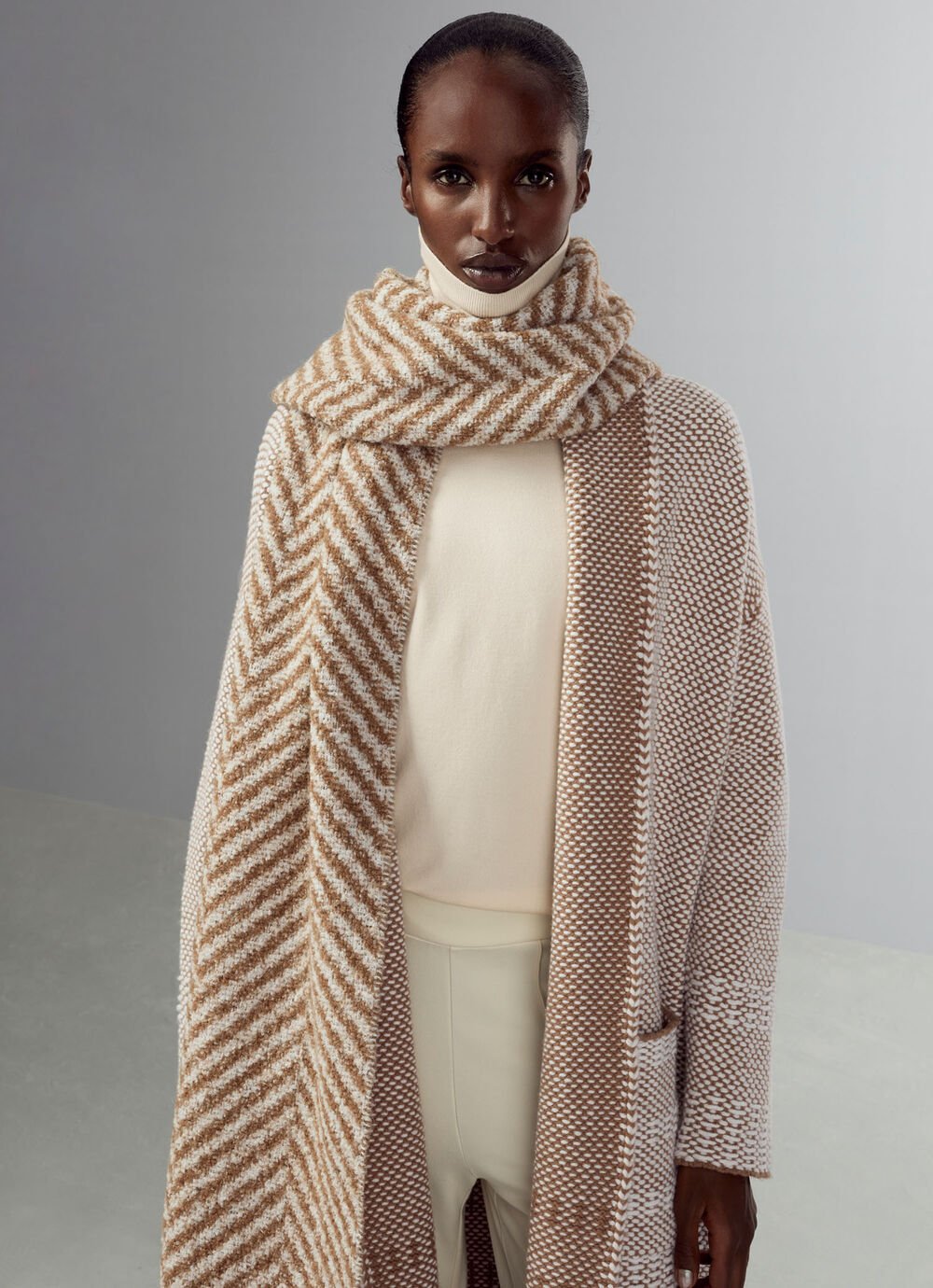Das Model trägt den übergroßen Bouclé-Schal Hailee mit Chevron-Muster in Braun und Creme.