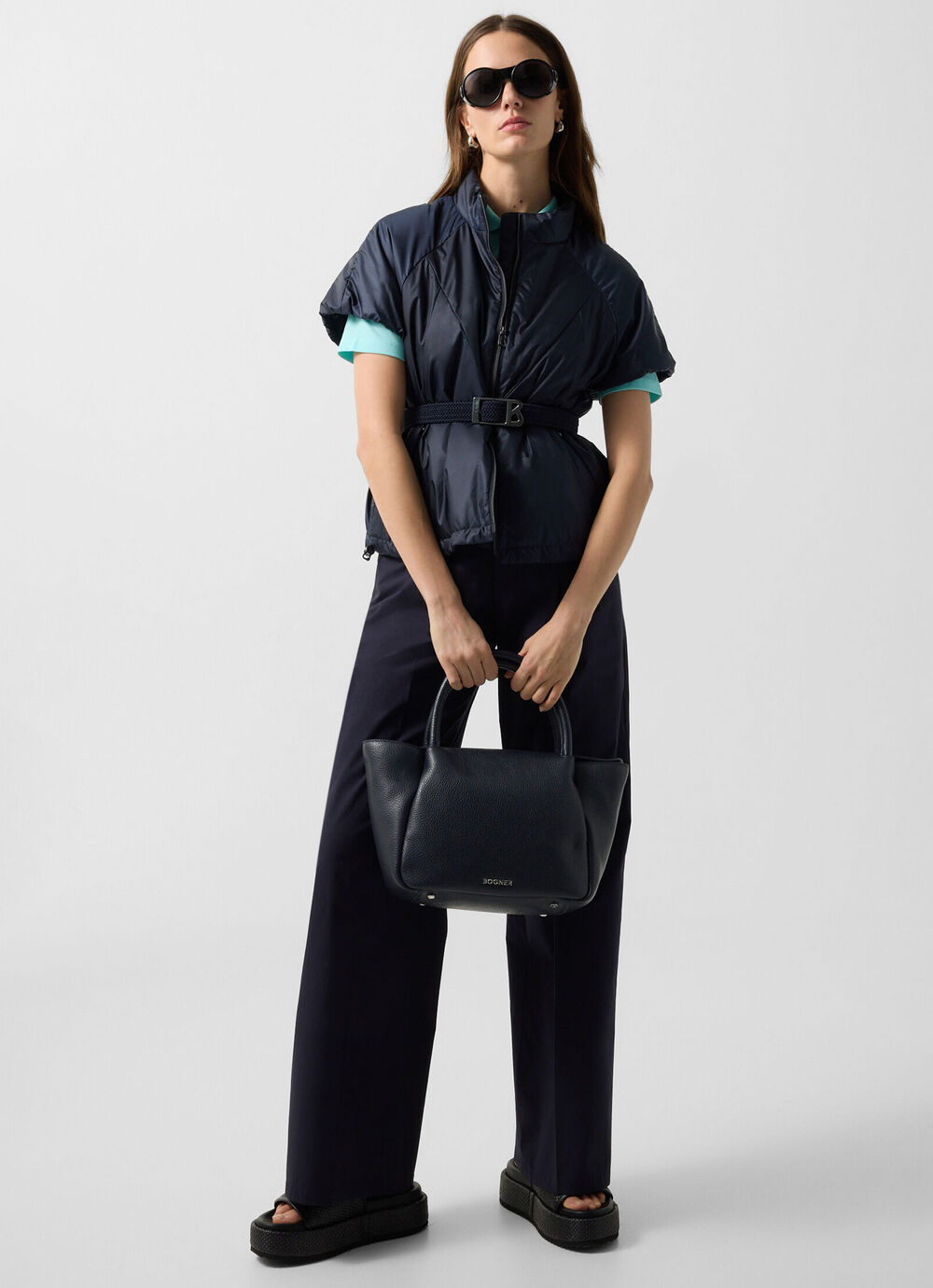 The female model is wearing the Brittany lightweight jacket in dark blue with matching trousers and a bag.