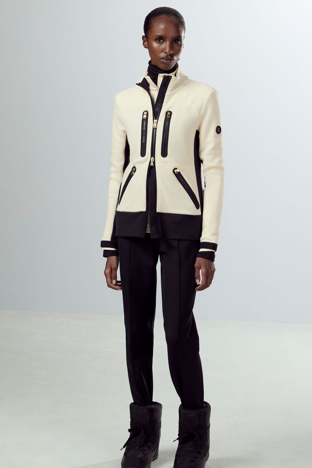 Ganzkörperaufnahme eines Damen Models, das Mid Layer Charlot, eine schwarze Hose und Winter-Boots kombiniert. Ganzkörperaufnahme eines Damen Models, das Mid Layer Charlot, eine schwarze Hose und Winter-Boots kombiniert.