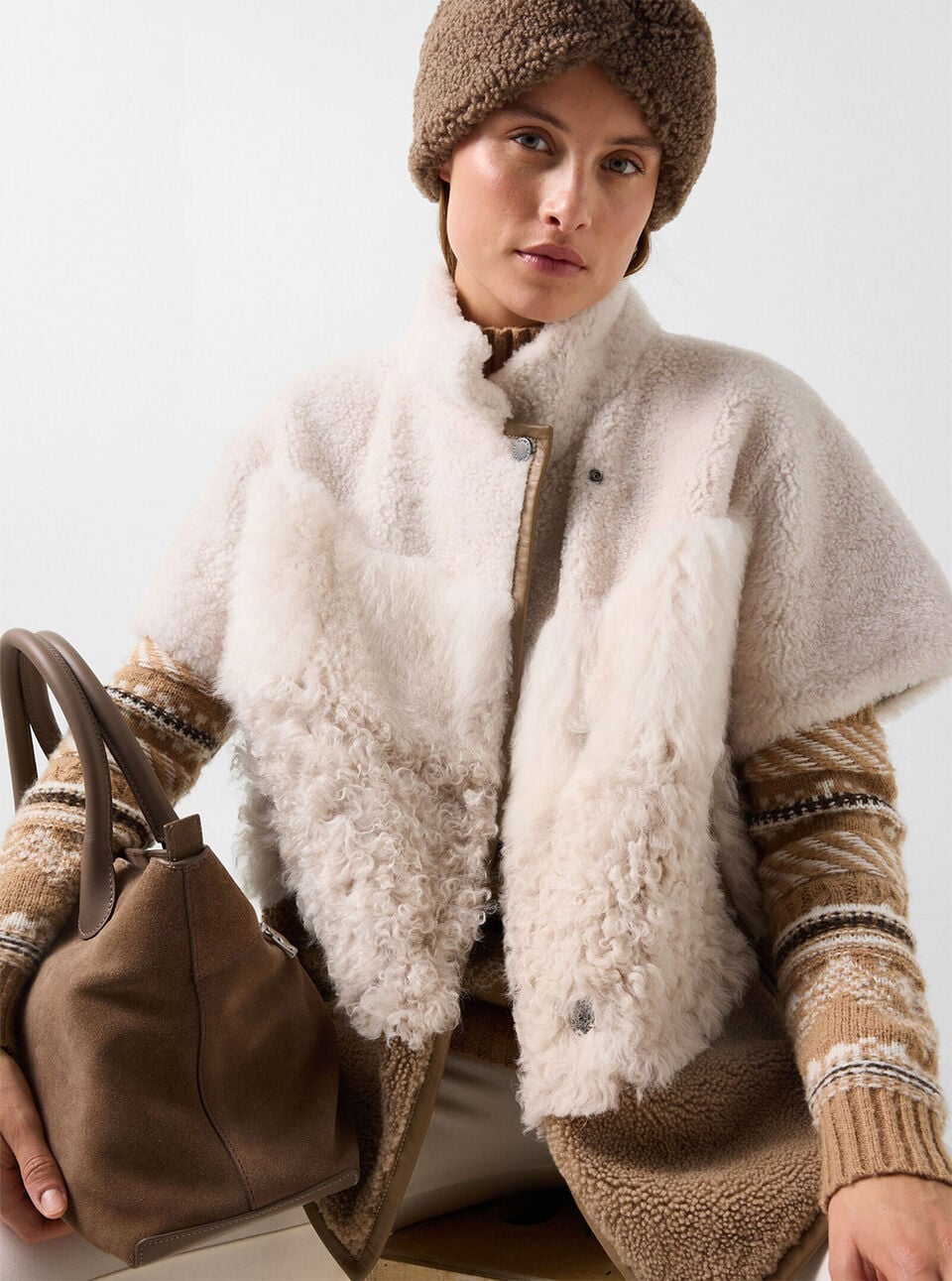The female model wears the Lexy shearling jacket in cream and brown, paired with the Justy teddy headband in Hazel and the Rosa Nordic sweater in Camel.