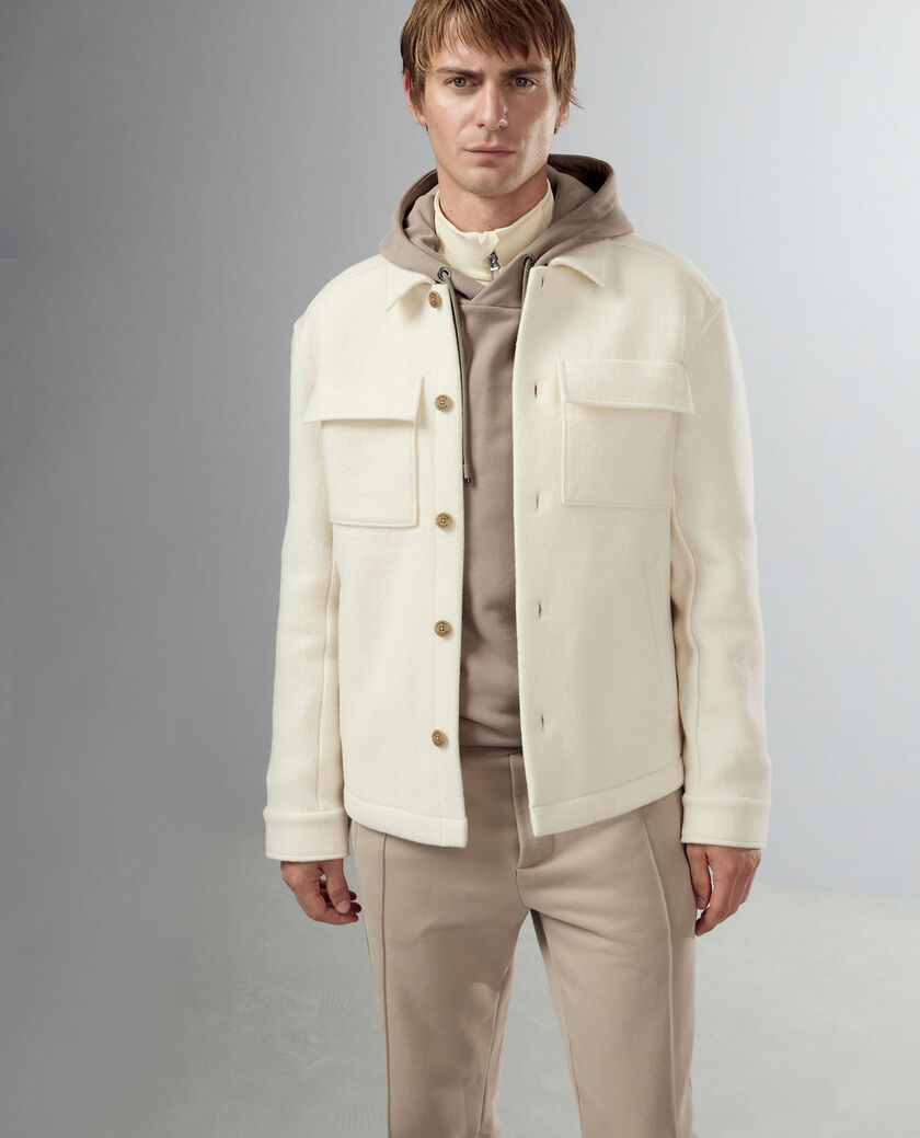 Die cremefarbene Herren Hemdjacke Archie aus reiner Wolle wird hier mit einem beigefarbenen Sweat-Look kombiniert.