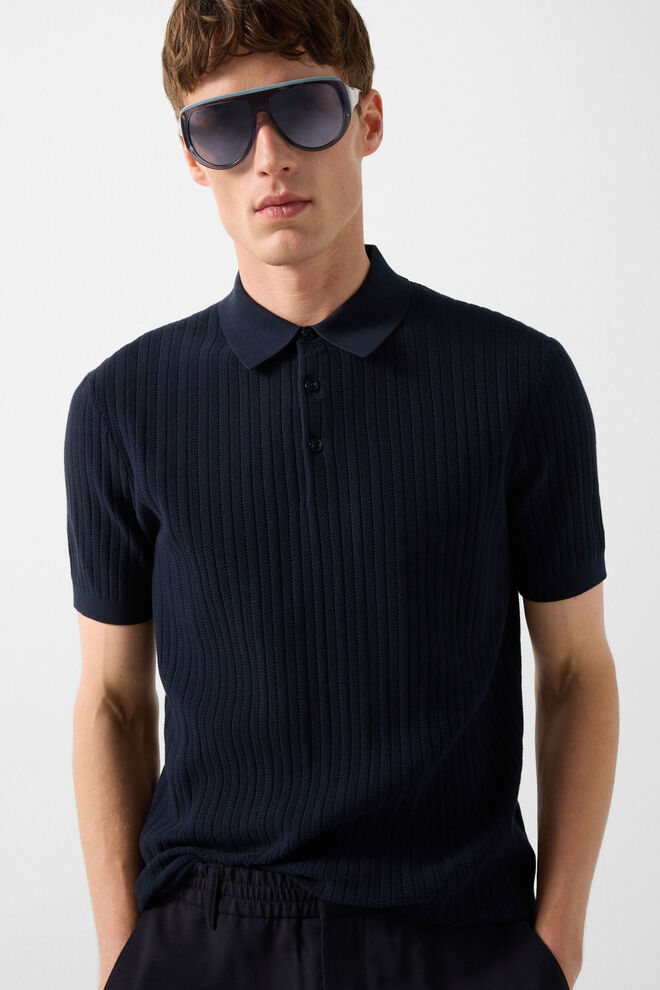 The male model is wearing a dark blue knitted polo shirt with a visible rib-knit pattern.