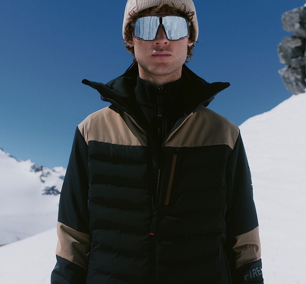 The male model is wearing a ski look in shades of brown, with ski goggles, a helmet and gloves adding a stylish finishing touch.