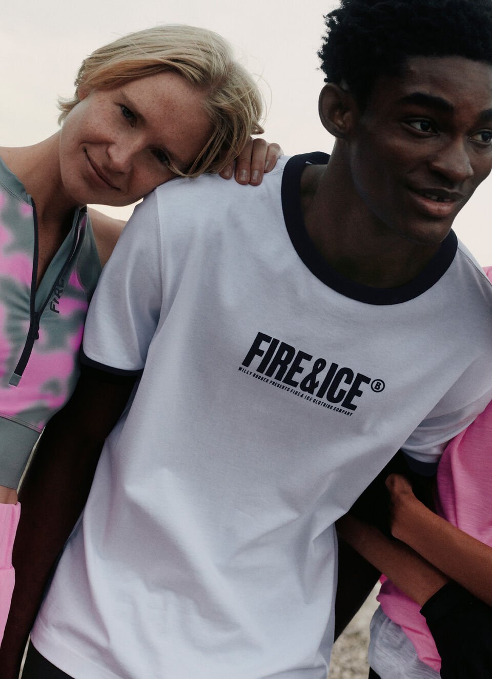 A group of three models, two female, one male, in FIRE+ICE looks. There is a lake in the background.