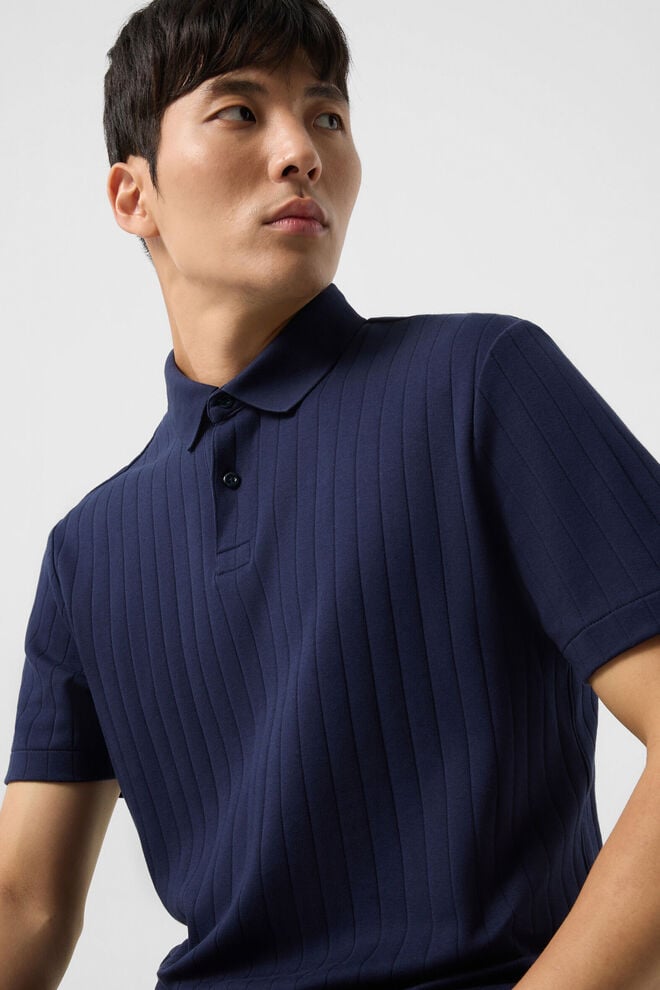 Das Herrenmodell tr&auml;gt das beigefarbene Polo-Shirt Timo, das mit einem dezenten Logodetail auf der Brust akzentuiert ist.