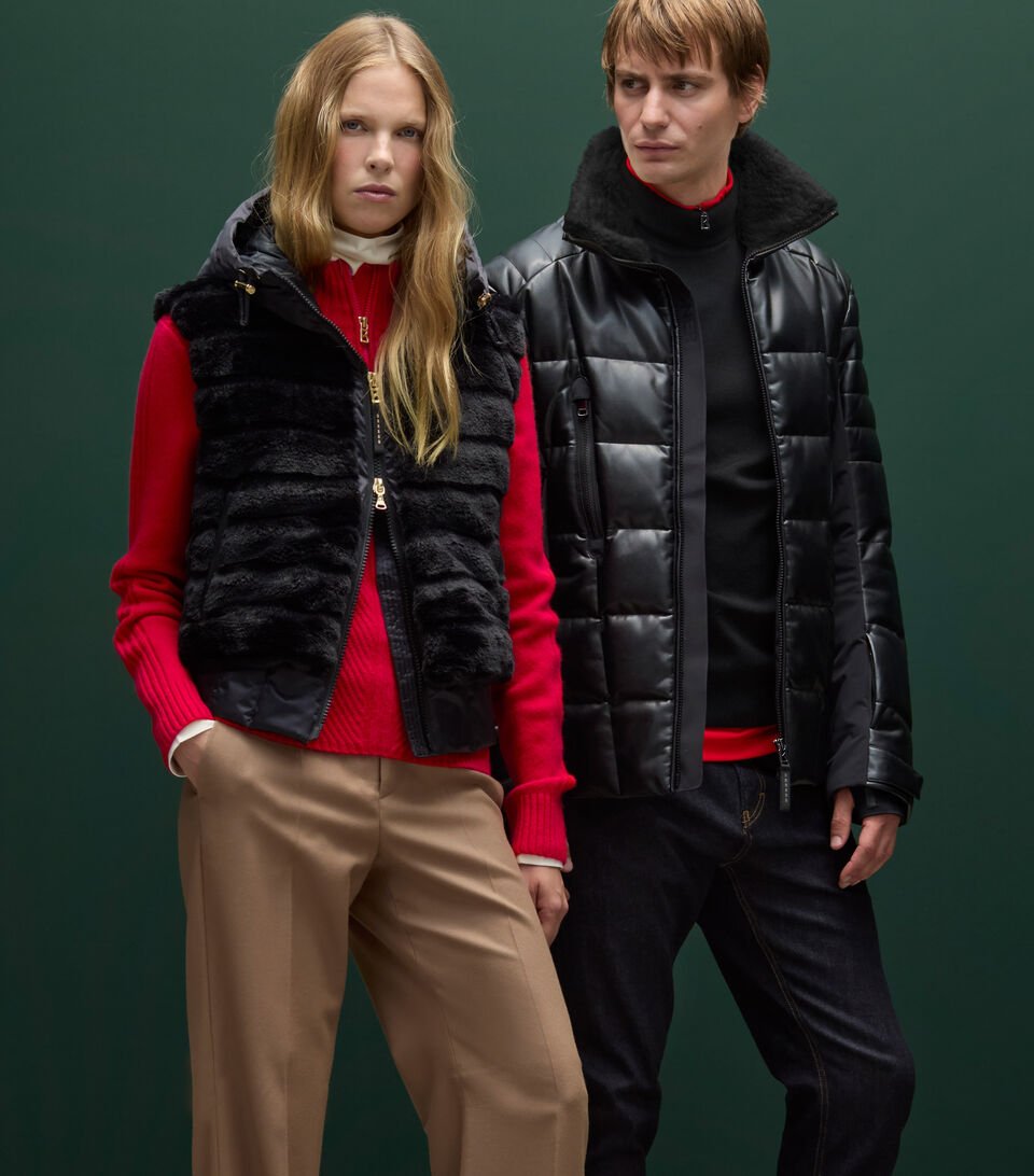 Couple Shot. Le mannequin femme porte un pull à col zippé et une veste sans manches bordée de fourrure, tandis que le mannequin homme arbore une doudoune effet cuir.