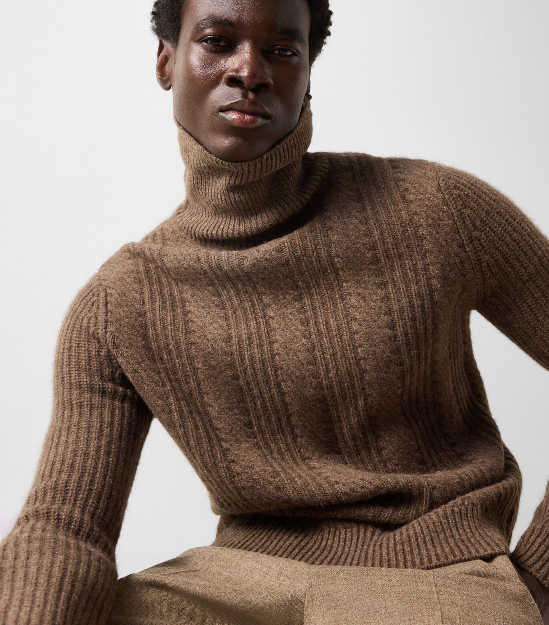 Le mannequin homme porte le pull Eros en laine de yak marron avec le pantalon Marcus en laine vierge m&eacute;lang&eacute;e.