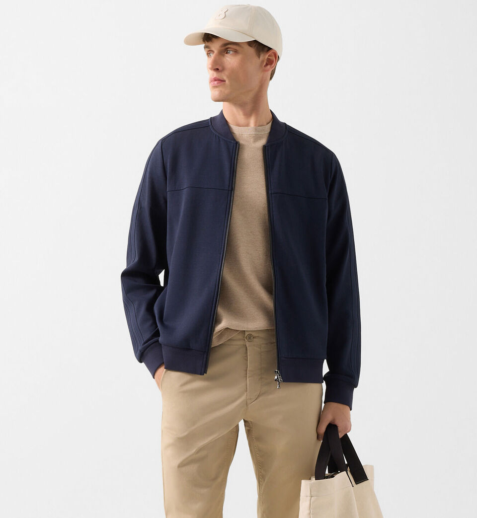 Halbk&ouml;rperaufnahme des Herren Models in Sweatjacke Lennox in Navy-Blau. Er tr&auml;gt dazu eine Basecap.