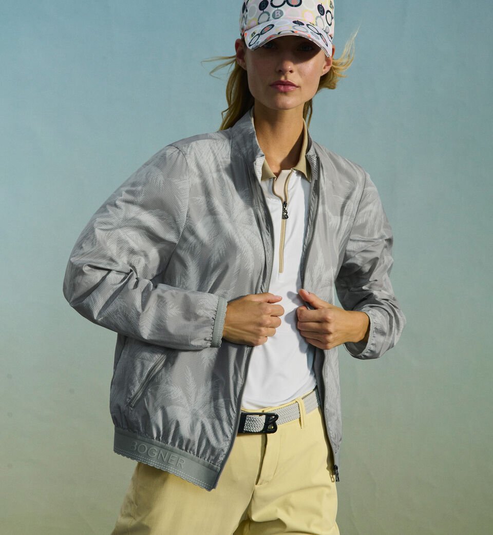 Das dunkelhaarige Damen Model in dynamischer Pose tr&auml;gt ein gelbes Polo-Shirt, dazu einen Faltenrock und Golf Sneaker.
