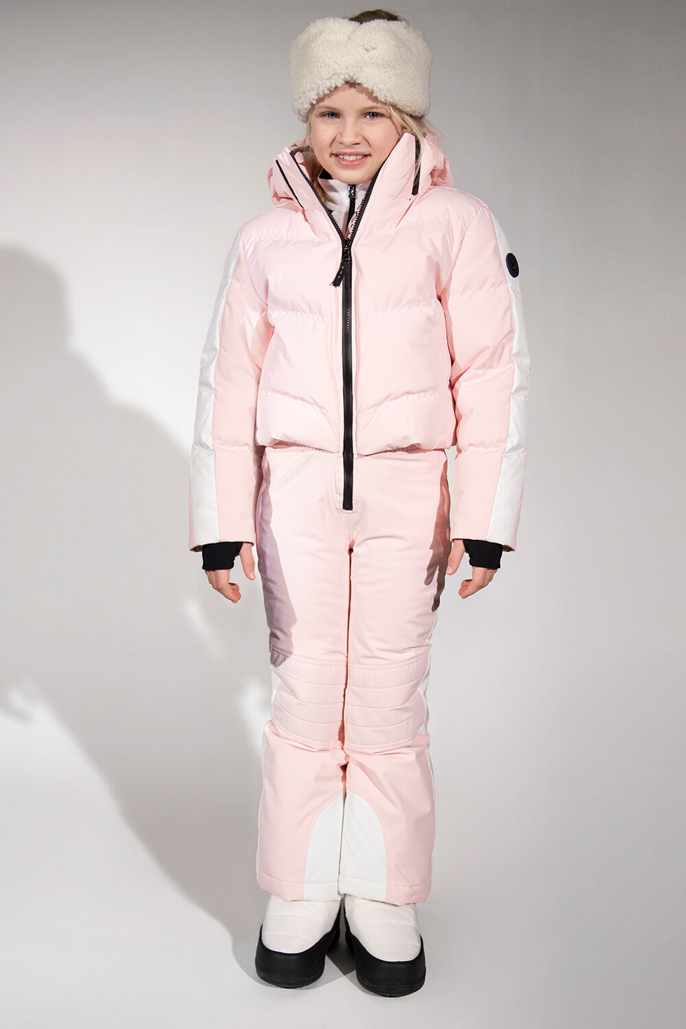Show ski overalls in pink are complemented here with a Justy teddy-fur headband and white boots.