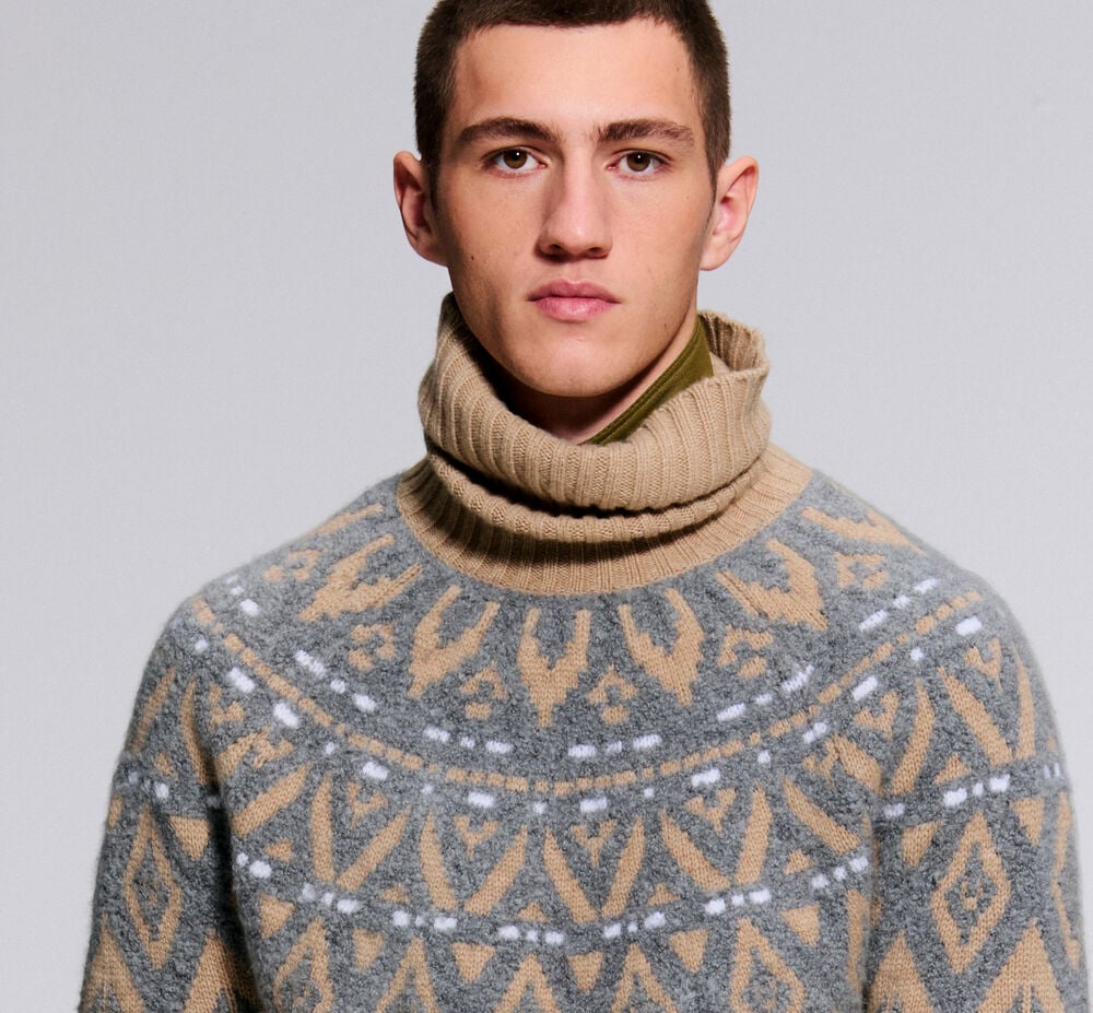 The male model is wearing the Roxter turtleneck pullover with a Norwegian pattern in beige and grey.