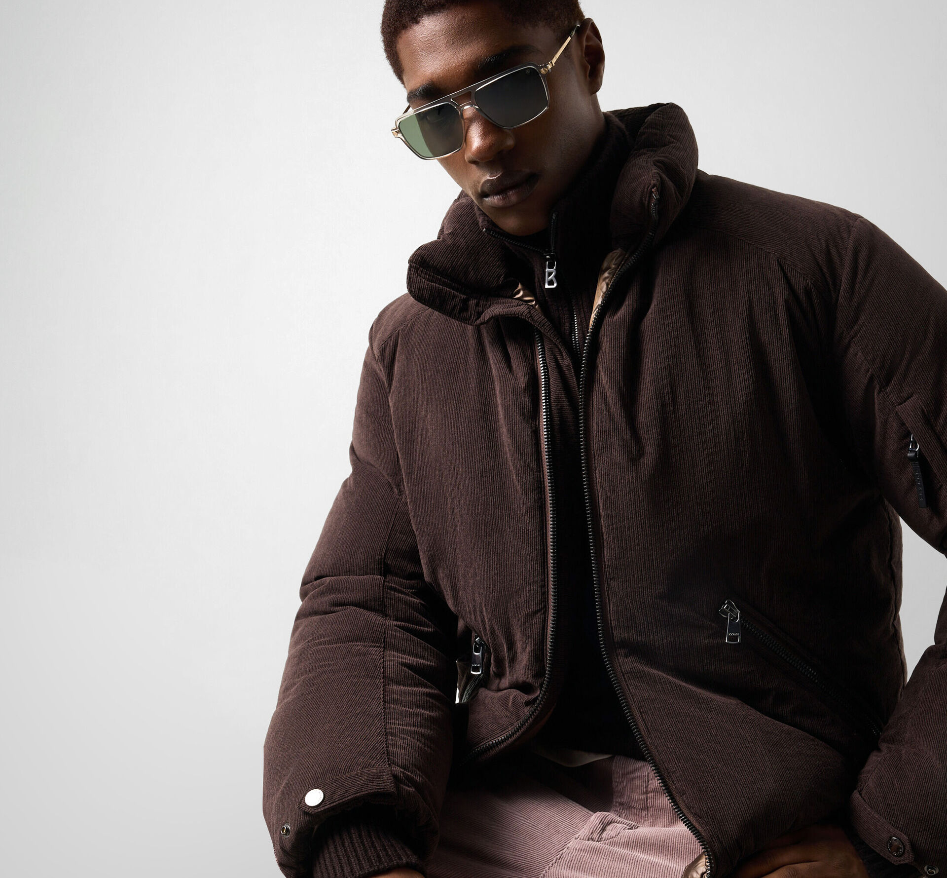 The model wears the dark brown Bert down jacket in corduroy, combining luxurious texture with functional performance.