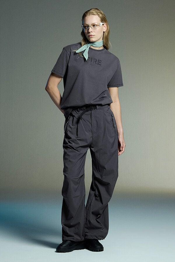 Das Model tr&auml;gt einen Monochrome Look in Grau, bestehend aus einem T-Shirt mit Logo-Print, Shell-Hose und Sneaker.