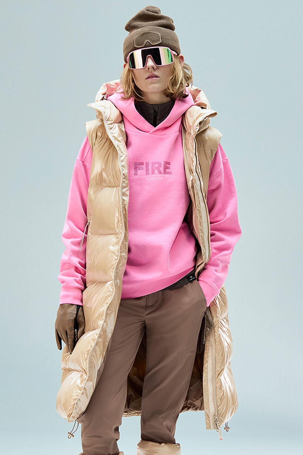  The female model is wearing a pink hoodie with Swarovski crystals and a long gilet.