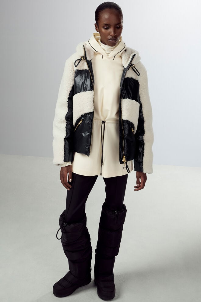 Das Damen Model trägt eine kurze Daunenjacke aus schwarzem Nylon, die mit kontrastierendem Fell besetzt ist. Das Damen Model trägt eine kurze Daunenjacke aus schwarzem Nylon, die mit kontrastierendem Fell besetzt ist.