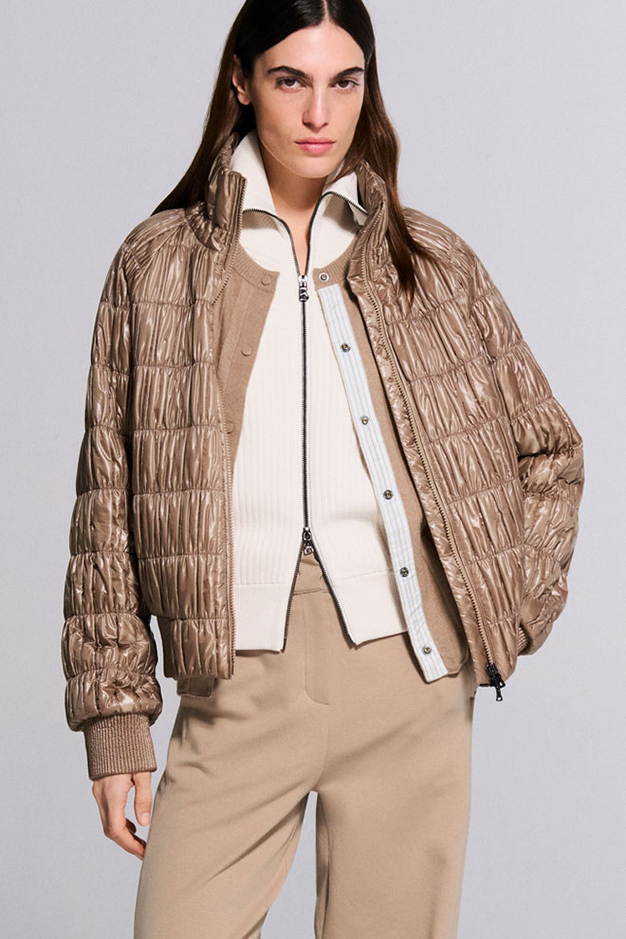 Das Damen Model tr&auml;gt Strickjacke Jana in Creme und Cardigan Tanja in Camel, dar&uuml;ber die farblich passende, in Streifen gesteppte Jacke Sherry.