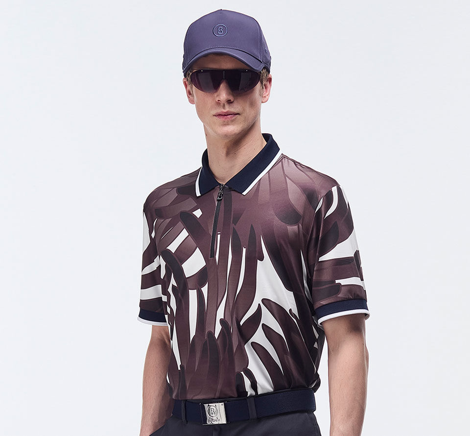 Das Herrenmodel präsentiert sich mit einem weinrot-weißen Polo-Shirt mit auffallendem grafischem Print. 