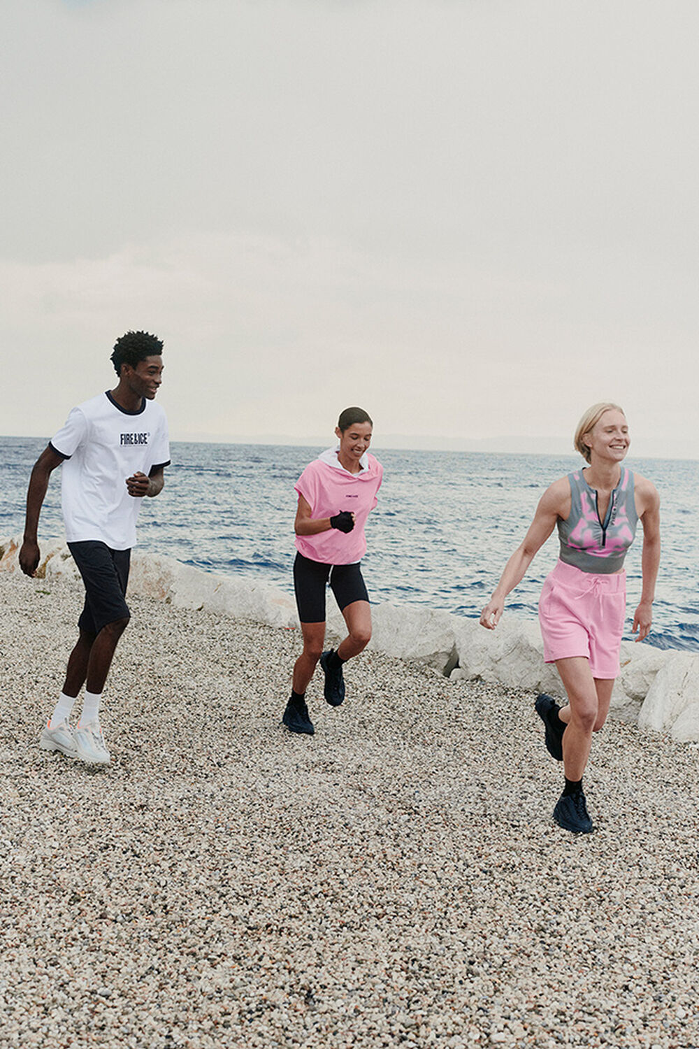 A group of three models walking along a beach. They are wearing summery FIRE+ICE beach and sportswear styles.