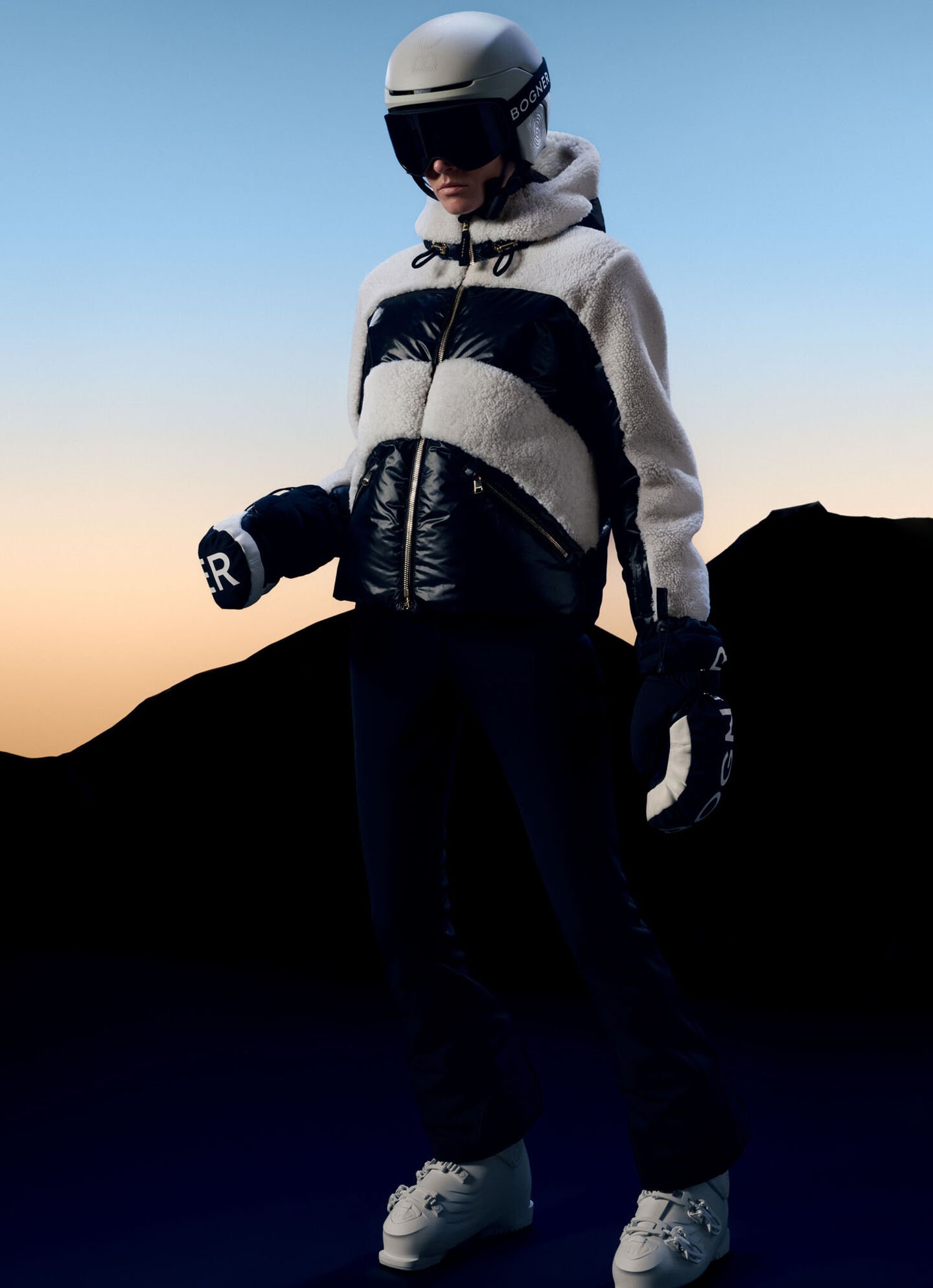 Das Model trägt eine Teddyfell-Jacke mit Leder-Partien und Ski-Equipment in Form von Handschuhen und eines Skihelms.