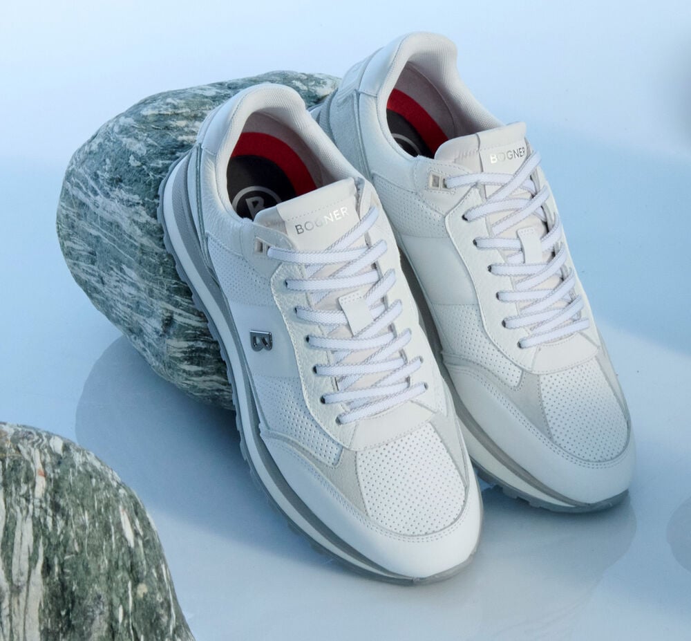 Aufnahme von BOGNER Sneakern, die an einem Stein lehnen. Sie sind in Wei&szlig; und Grau gehalten.